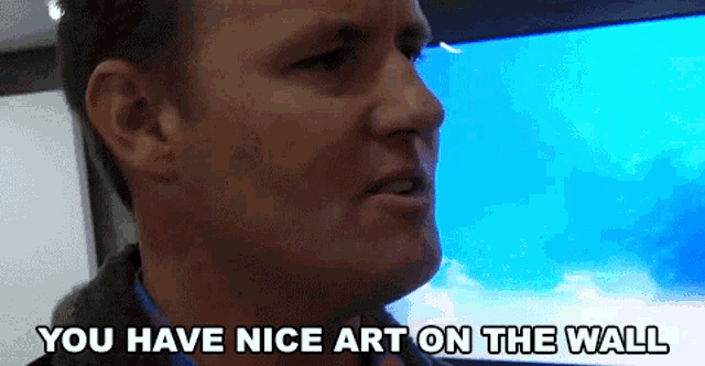 a man says " you have nice art on the wall " in front of a blue screen