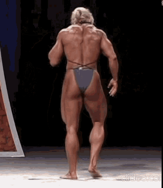 a female bodybuilder is standing on a stage wearing a blue bikini .