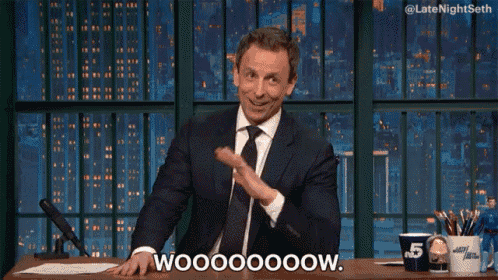 a man in a suit and tie says wooooooow while sitting at a desk