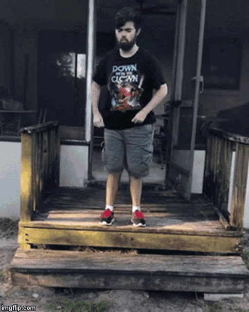 a man wearing a down and clean shirt stands on a set of wooden stairs