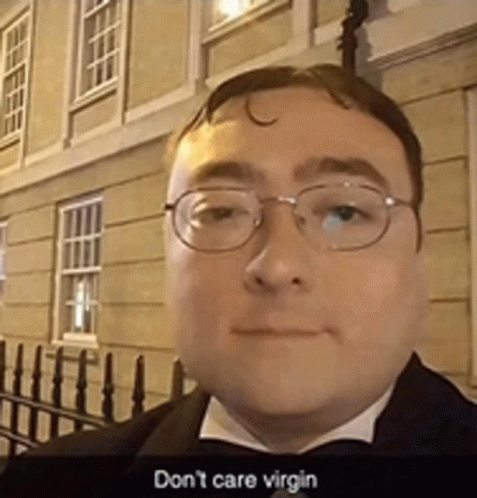 a man wearing glasses and a tuxedo says " do n't care virgin " in front of a building