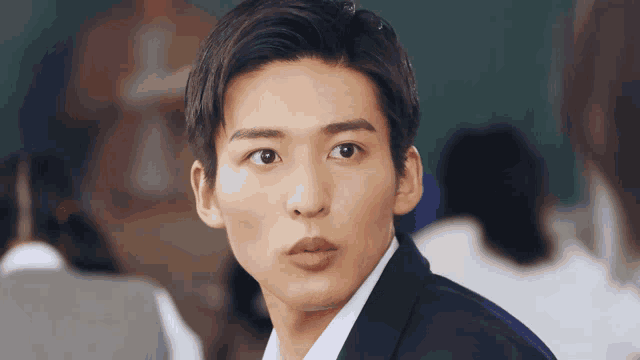 a young man in a suit looks at the camera with a serious look on his face