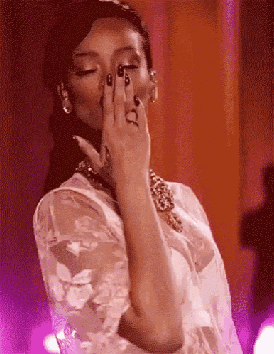 a woman is covering her face with her hand while wearing a white dress .