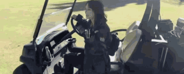 a woman is sitting in a golf cart on a grassy field .