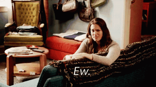 a woman sitting on a couch with the word ew written on the couch