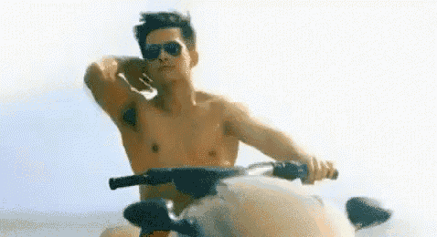 a shirtless man is riding a jet ski in the ocean .