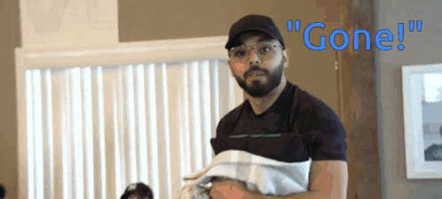 a man with a beard and glasses is holding a blanket and says " gone " in blue