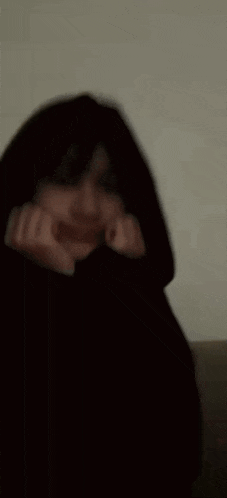 a blurry picture of a person wearing a black hooded jacket .