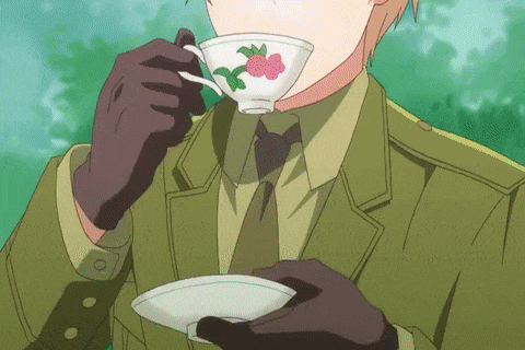 a man in a suit and tie is drinking from a white cup with a flower on it