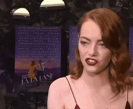 a woman in a red dress stands in front of a poster for la la land