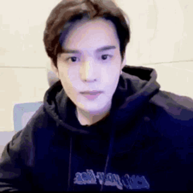 a close up of a man wearing a black hoodie and looking at the camera .