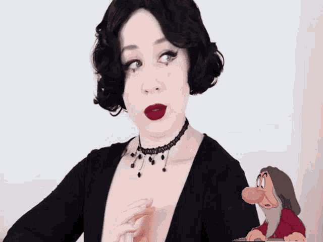 a woman in a black dress is standing next to a cartoon character with a red beard .