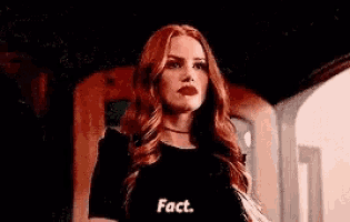 a woman with red hair and red lipstick is standing in front of a door .