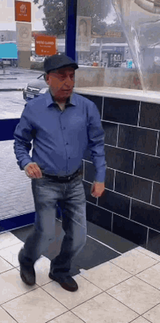 a man wearing a hat and a blue shirt is walking in front of a store .