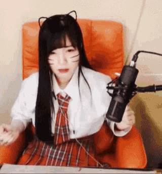 a young girl is sitting in an orange chair holding a microphone .