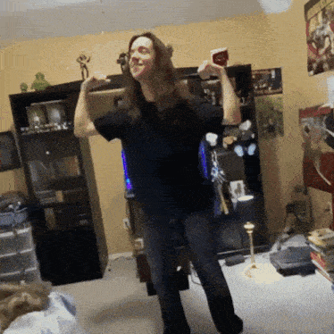 a woman is dancing in a living room with a poster on the wall that says ' avengers '