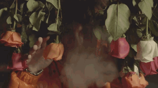 a man in an orange jacket is surrounded by flowers and smoke