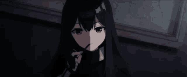 a girl with long black hair is eating a candy bar in a dark room .