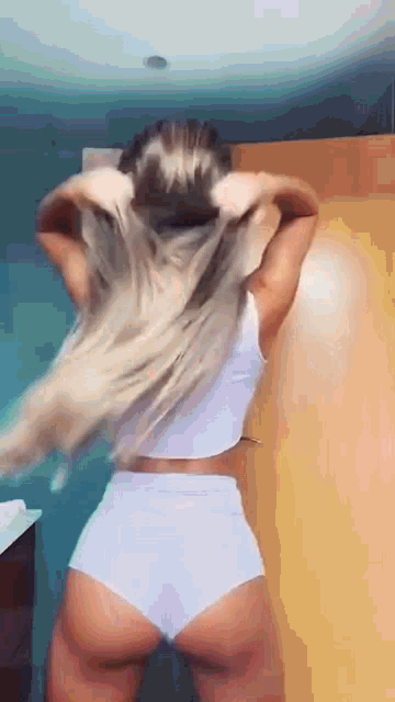 a woman in a white top and shorts is standing in front of a door .