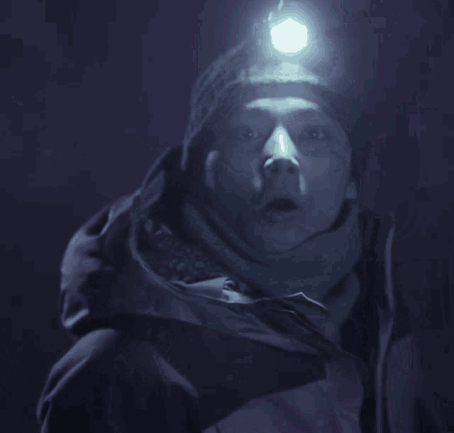 a man with a headlamp on his head is smoking a cigarette