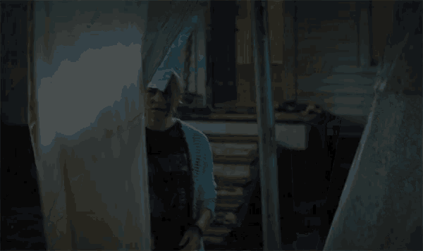 a woman wearing a t-shirt that says ' nirvana ' on it looks out of a window