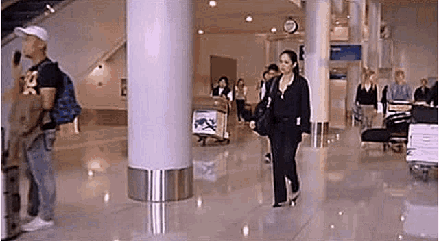 a woman is walking down a hallway at an airport .