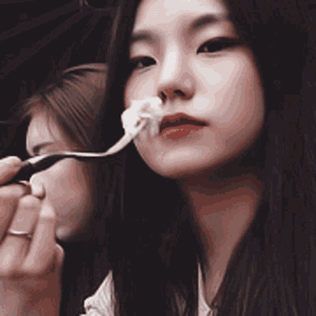 a woman is eating something with a fork in her mouth while another woman looks on