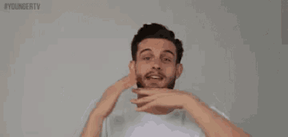 a man with a beard is making a funny face with his hands outstretched .