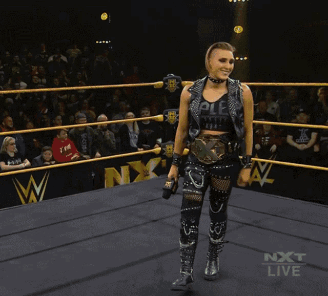 a woman is standing in a wrestling ring with the words next live on the bottom