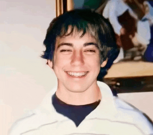 a young man is smiling in front of a picture