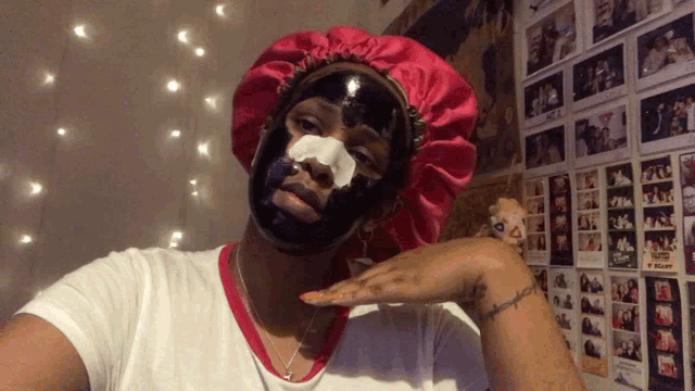 a woman wearing a black mask and a pink hat is taking a selfie