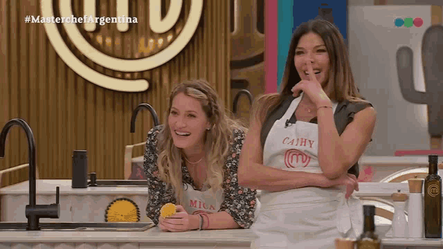 two women wearing aprons one of which says cahy