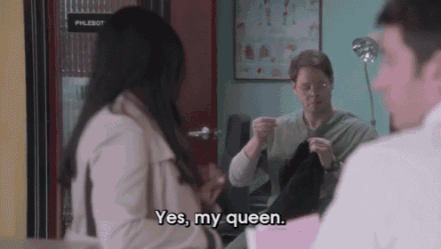 a woman says yes my queen while talking to a man in a lab coat