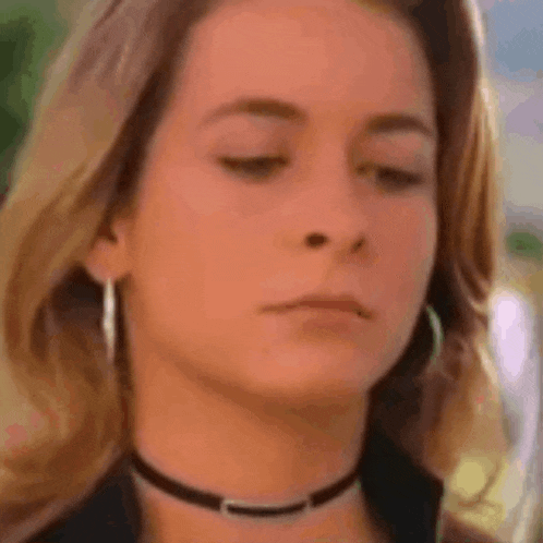 a close up of a woman 's face wearing a choker and hoop earrings .