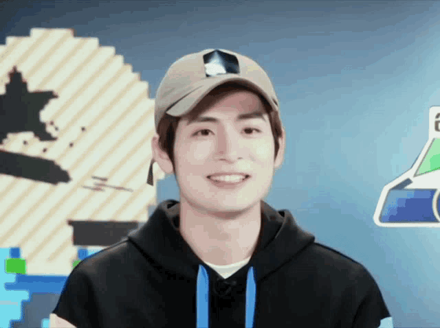 a young man wearing a hat and a hoodie smiles for the camera