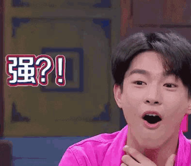 a man in a pink shirt is making a funny face in front of a sign that says ? !
