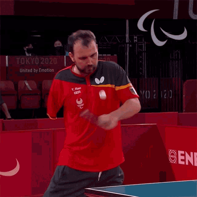 a man playing ping pong in front of a tokyo 2020 sign