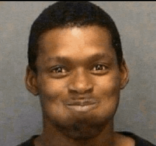 a man with a beard is smiling for the camera in a mug shot .