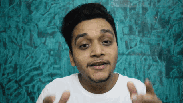 a young man with a beard wearing a white shirt making a funny face