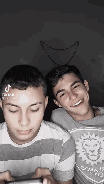 two young men are posing for a picture and one of them is wearing a gray shirt with a lion logo on it