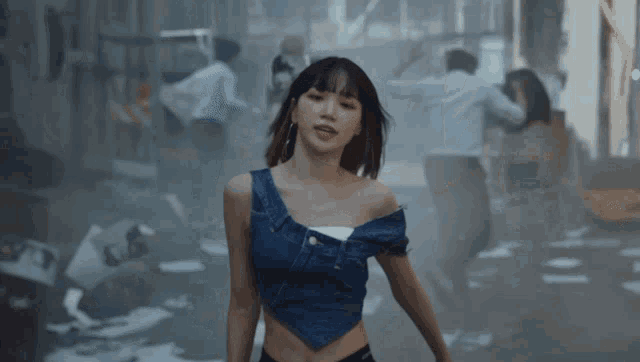 a woman in a denim crop top stands in a crowded street