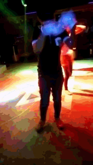 a man wearing a black shirt with the letter k on it is dancing in a dark room