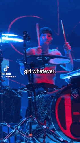 a shirtless man is playing drums on a stage with a caption that says ' girl whatever ' .