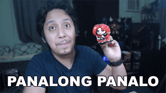 a man in a black shirt is holding a red figurine with the words panalong panalo written below him