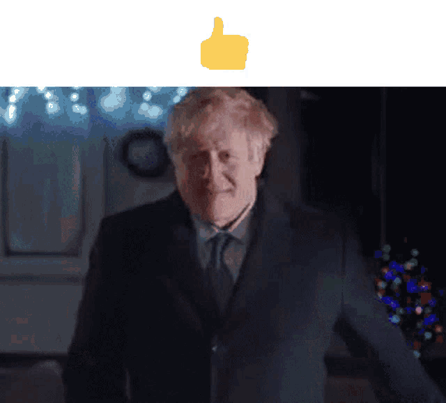 a man in a suit giving a thumbs up