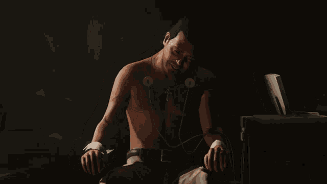 a shirtless man with a cross around his neck is sitting in a chair