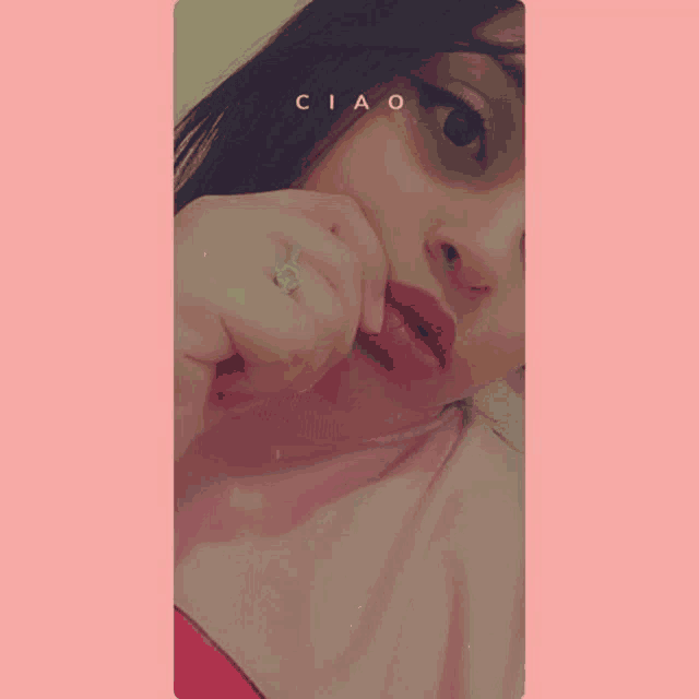 a woman wearing a ring on her finger is taking a selfie with her hand to her face .