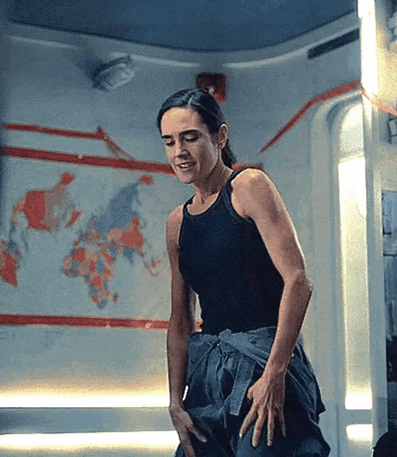 a woman in a tank top is standing in front of a map of the world .