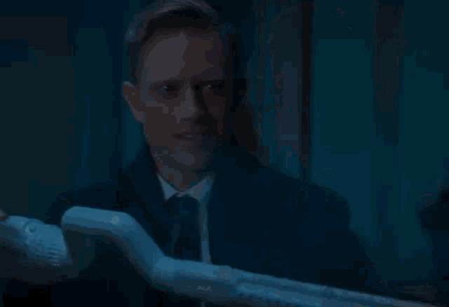 a man in a suit and tie is holding a glowing stick in his hand .