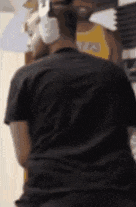 a man in a black shirt is standing in front of a mirror looking at himself .